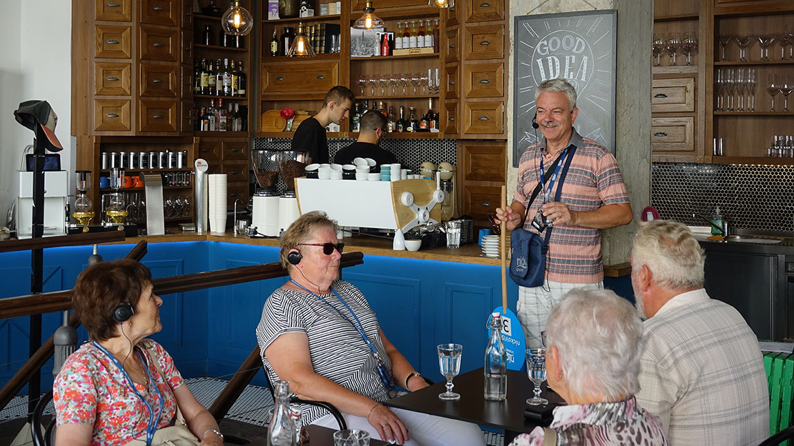 Reiseleiter gibt in einem Café Erklärungen zur Stadt ab